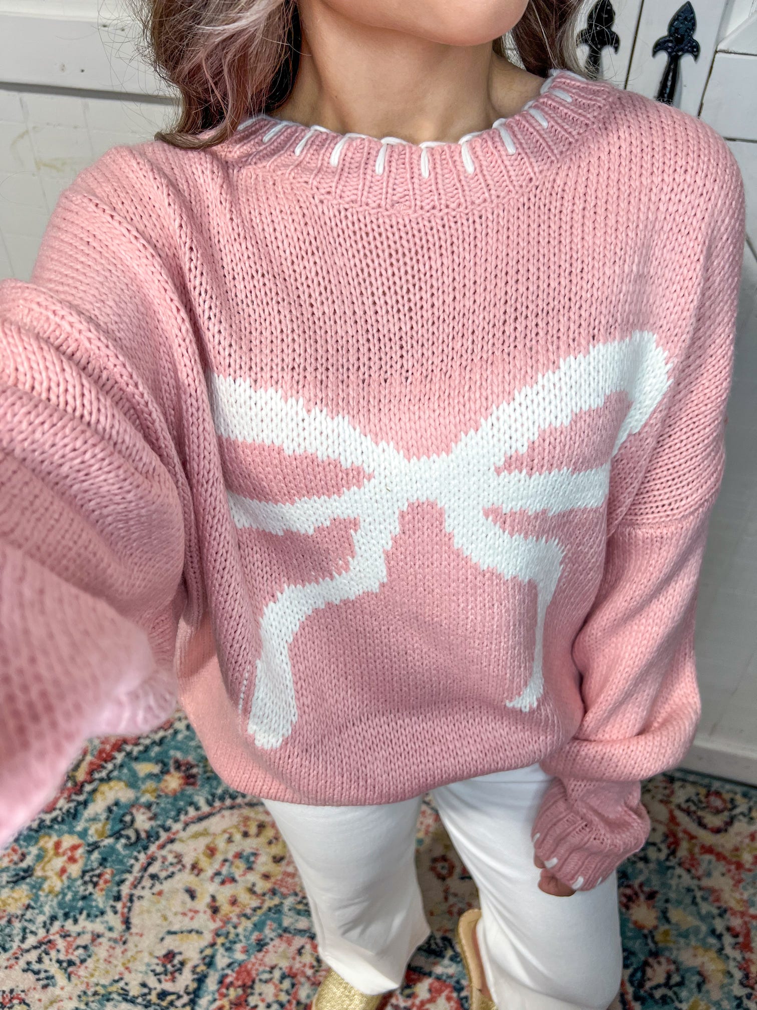 Up close photo of our pink long sleeve sweater with a huge white bow on the front