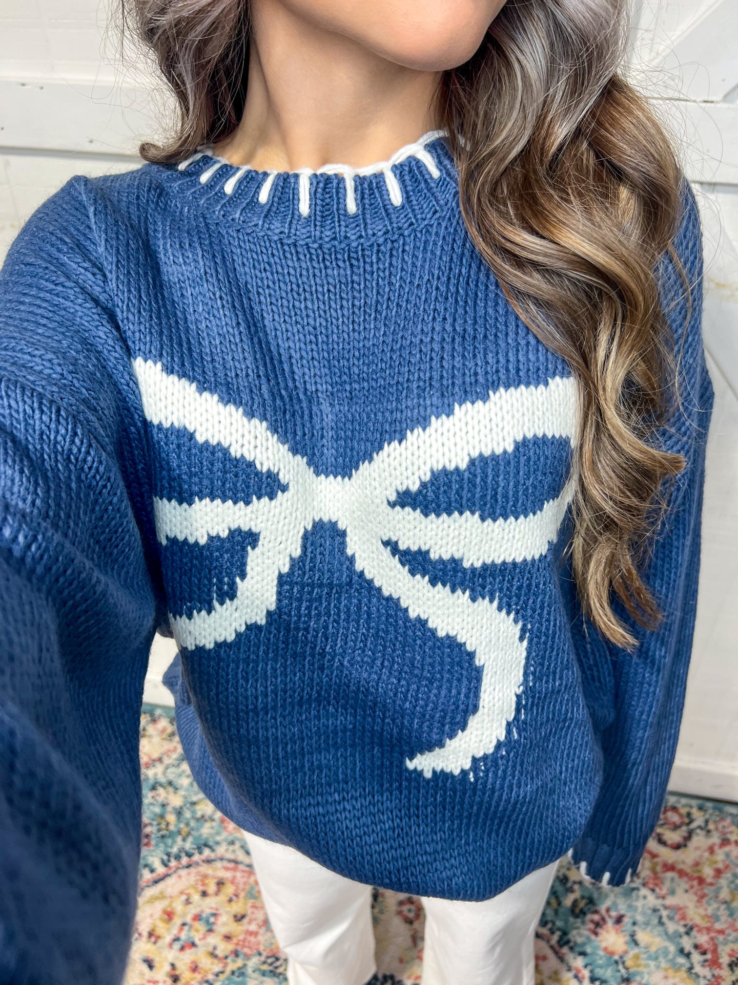 Up close photo of our navy long sleeve sweater with a huge white bow on the front