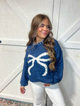 Photo of a woman modeling our navy long sleeve sweater with a huge white bow on the front