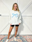 Woman modeling a light grey sweatshirt with a big bow on the front in turquoise blue