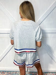 Woman modeling the back of the grey shorts set with red, white and blue sequins trim around bottom of shirt and shorts