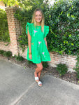 Woman modeling a kelly green tiered mini dress with sequined margarita glasses all over. It has a cap ruffle sleeve.