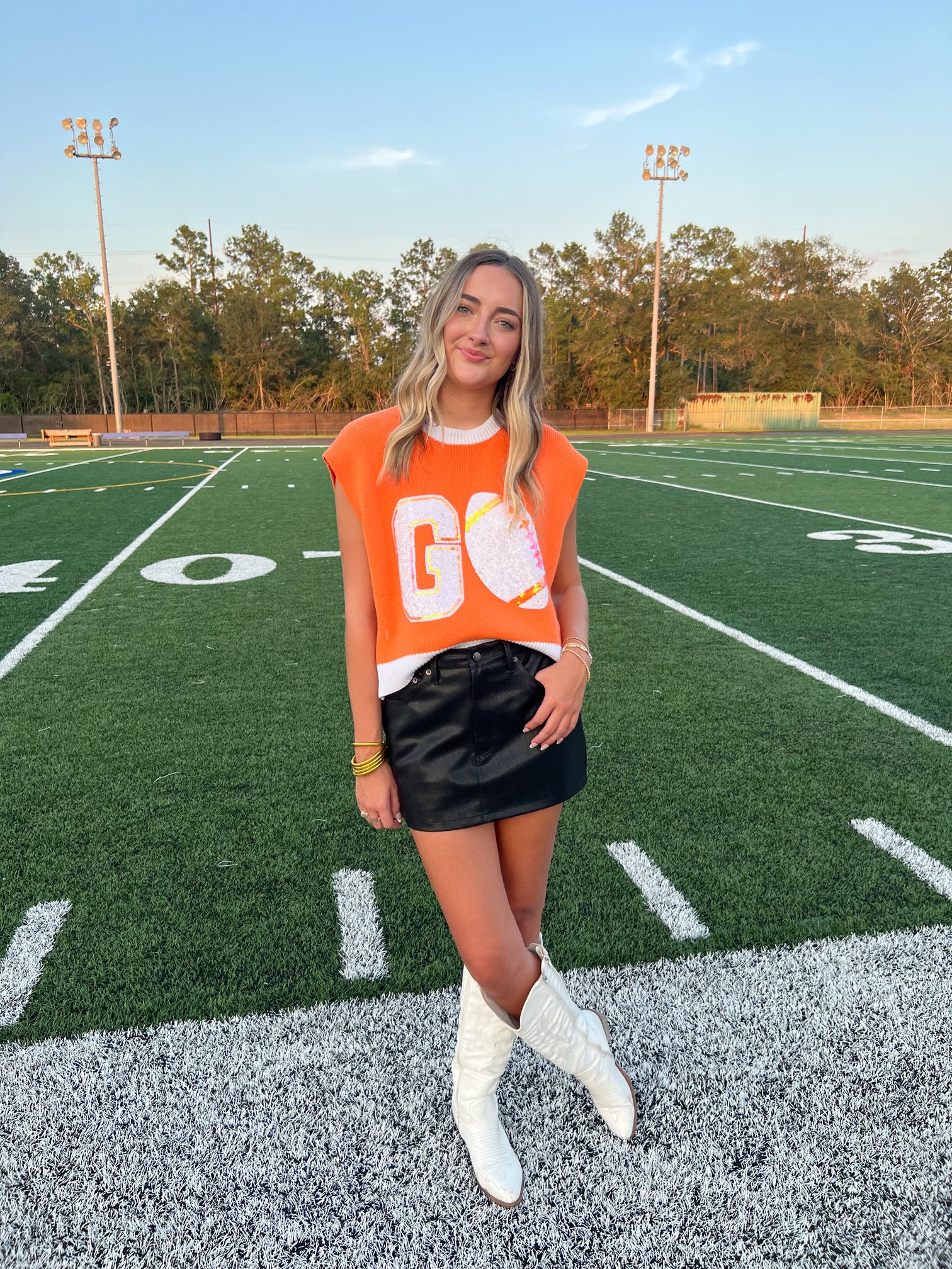 Woman modeling our black pleather skirt with pockets standing on a football field.