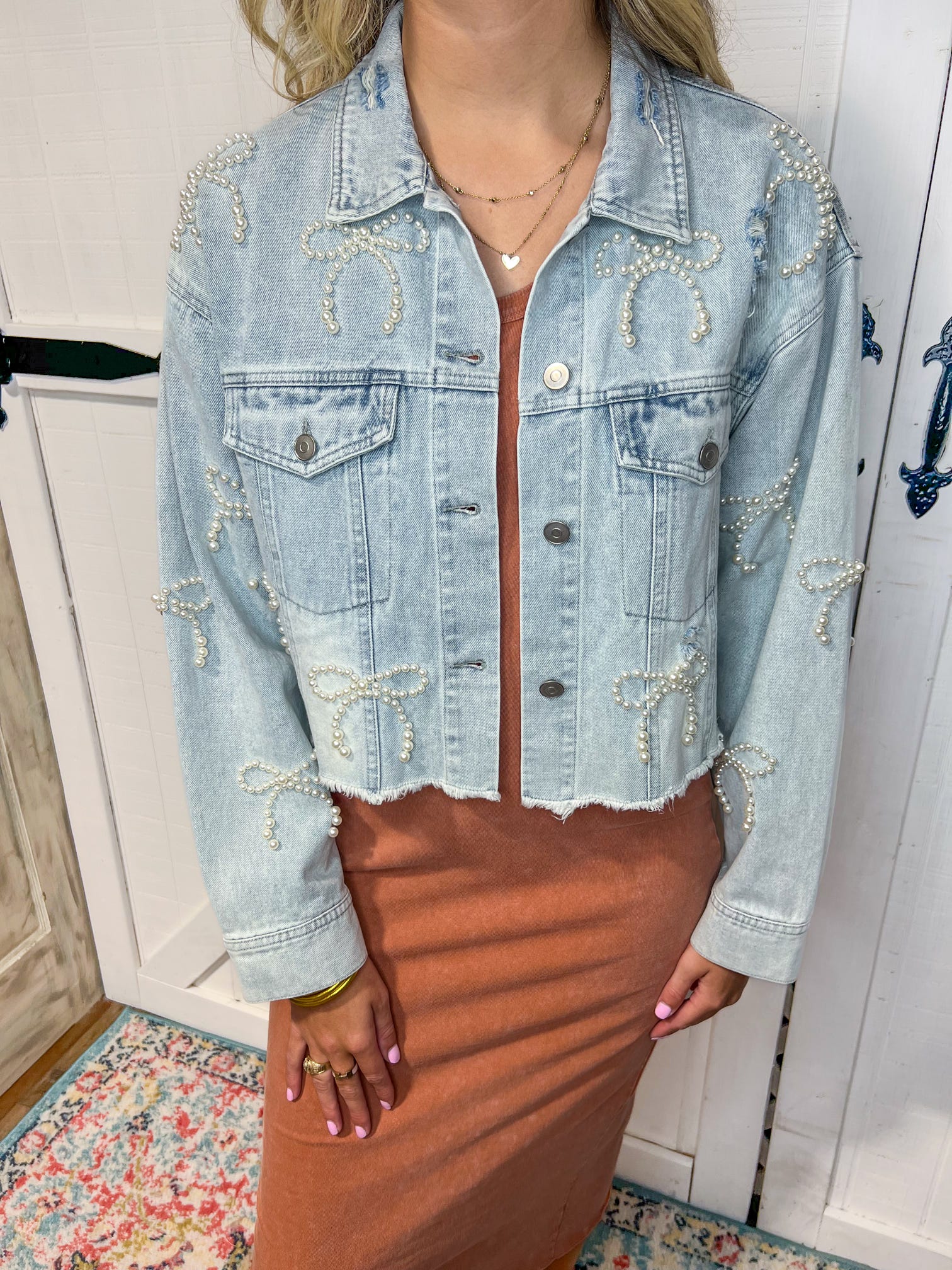 Up close photo of our light denim jean jacket with bows all over made of white pearls. 