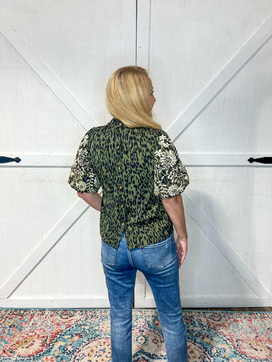 Photo of the back of our dark green top featuring a cheetah pattern and playful cream floral embroidery on the sleeves