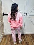 Young woman modeling the back of our two piece pink lounge set including a light hoodie sweatshirt and sweatpants.