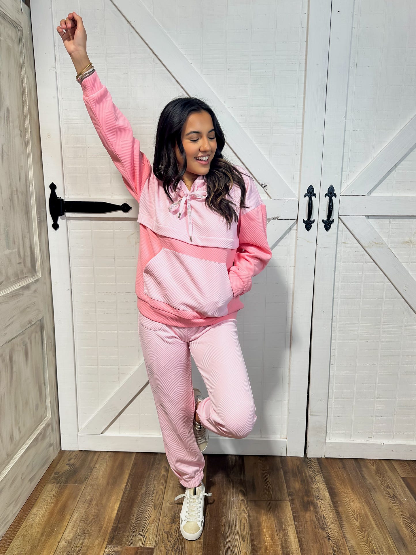 Another photo of a young woman modeling our two piece pink lounge set including a light hoodie sweatshirt and sweatpants.