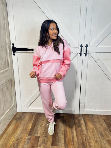 Young woman modeling our two piece pink lounge set including a light hoodie sweatshirt and sweatpants.