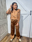 Young woman modeling a short sleeve blouse with a cap ruffle sleeve in warm fall colors of rust, brown, and pink