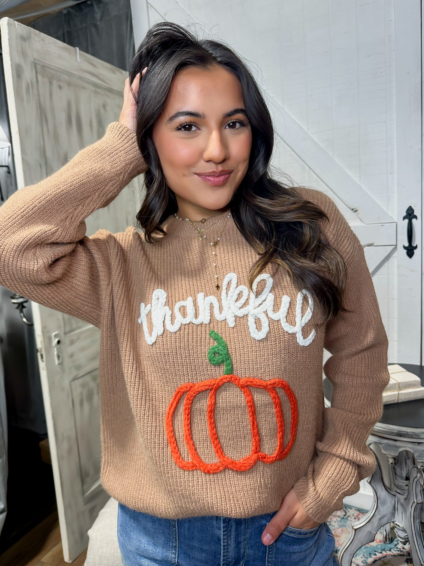 Up close photo of our brown sweater with Thankful and a pumpkin stitched in yarn on the front