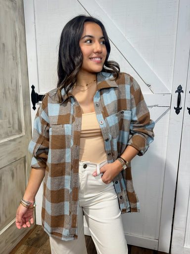 Young woman modeling a brown and light blue plaid button down shacket