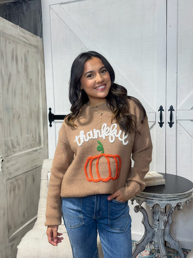 Young woman modeling our brown sweater with Thankful and a pumpkin stitched in yarn on the front