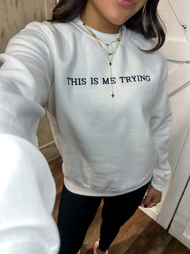 Up close photo of our white crew neck sweatshirt saying "This is Me Trying" embroidered in navy on the front across the chest area