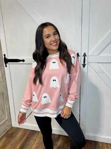 Young woman modeling our light pink sweatshirt that is covered in white sequin ghosts