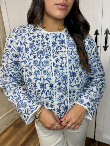 Up close photo of our white quilted jacket with a blue floral pattern all over