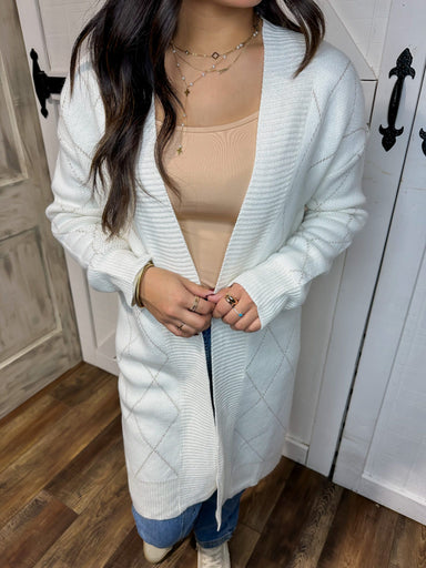 Up close photo of our white long cardigan with gold stitching in an X pattern all over