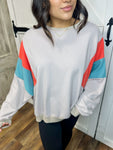 Up close photo of our beige lightweight sweatshirt featuring a bold orange and turquoise stripe on the arms.