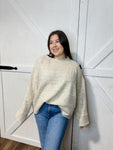 Woman modeling our cream long sleeve sweater with wide sleeves