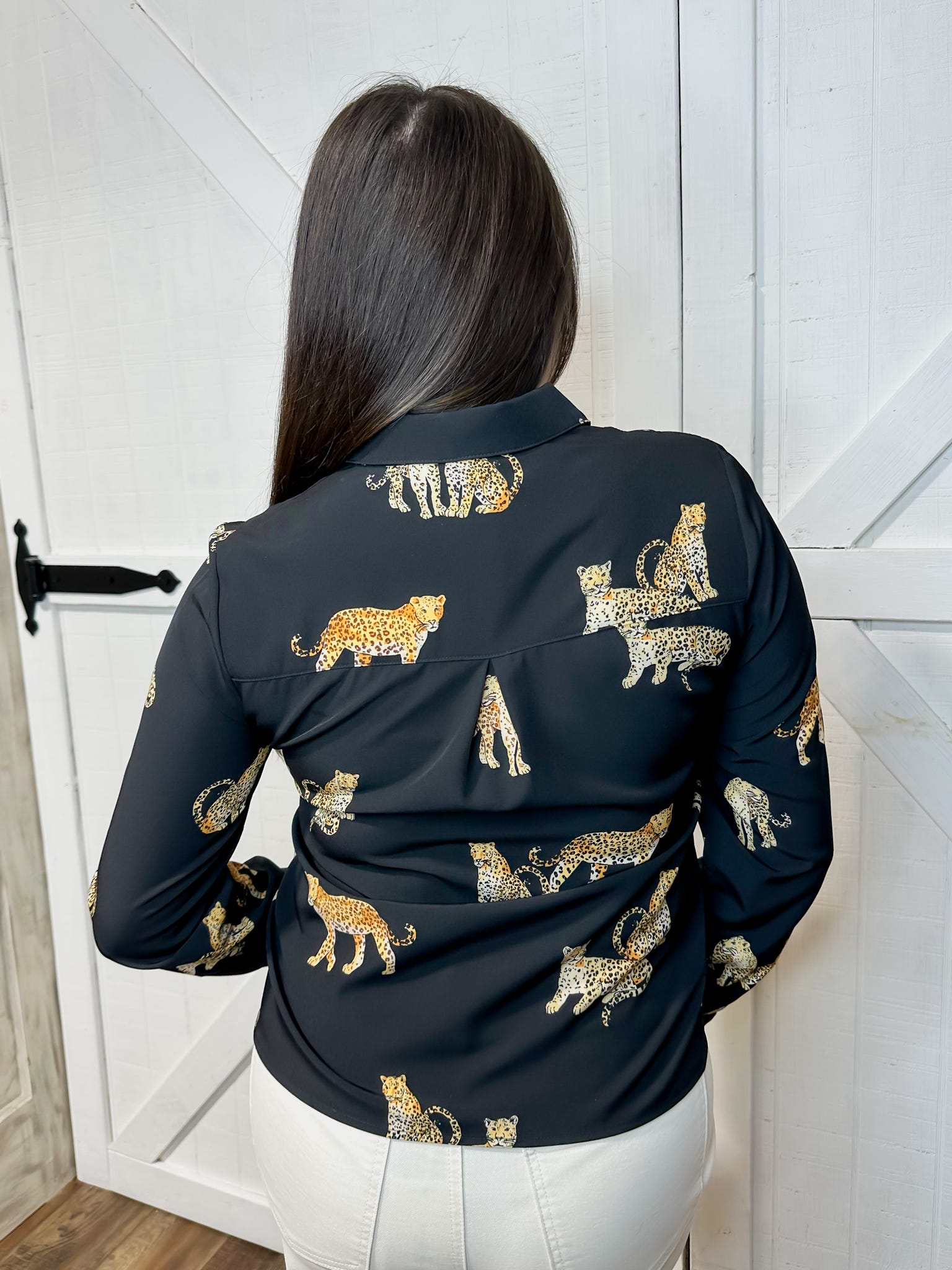 Young woman modeling the back of our black, button down, long sleeve blouse with cheetah animals all over.