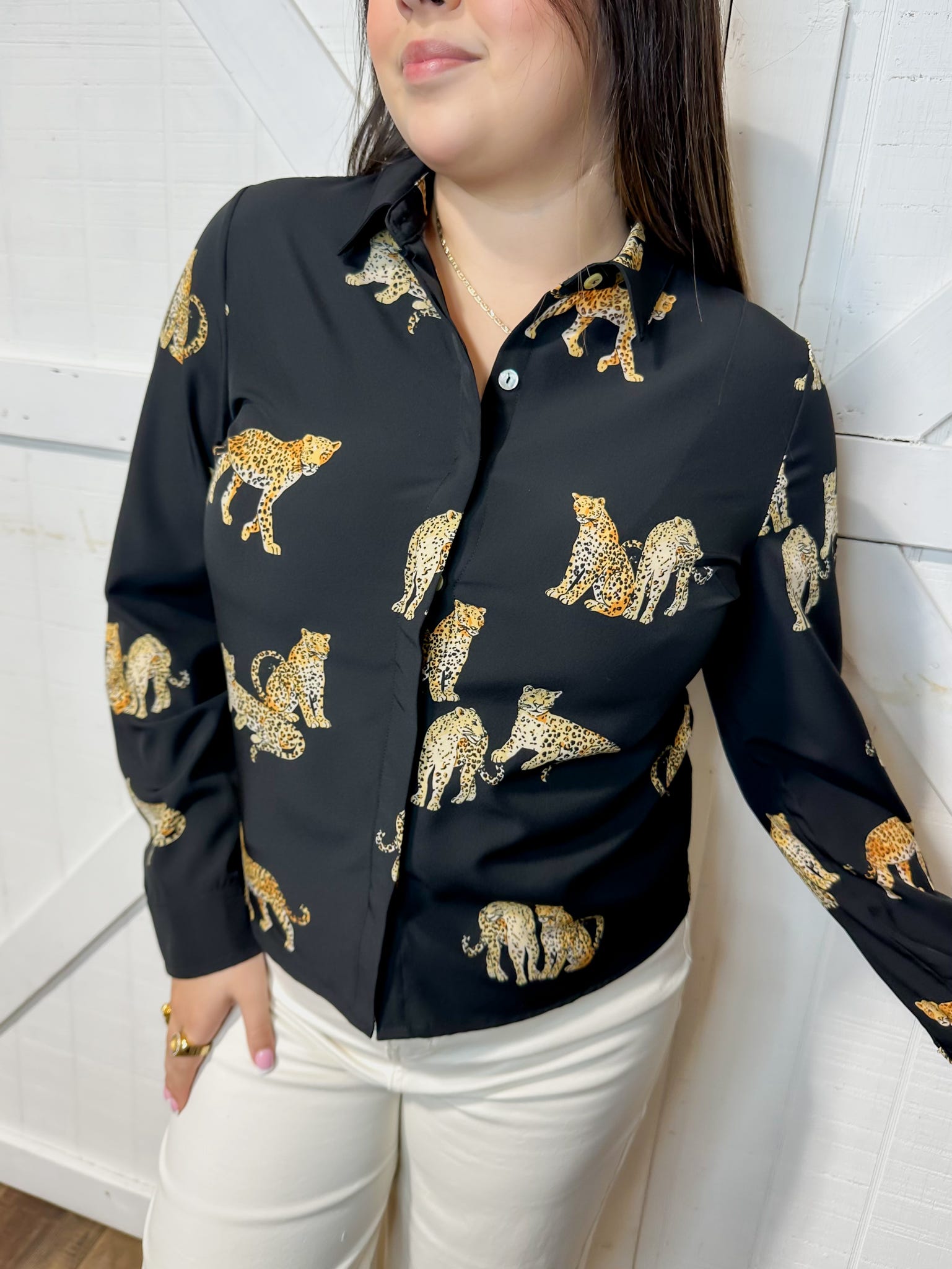 Young woman modeling our black, button down, long sleeve blouse with cheetah animals all over.