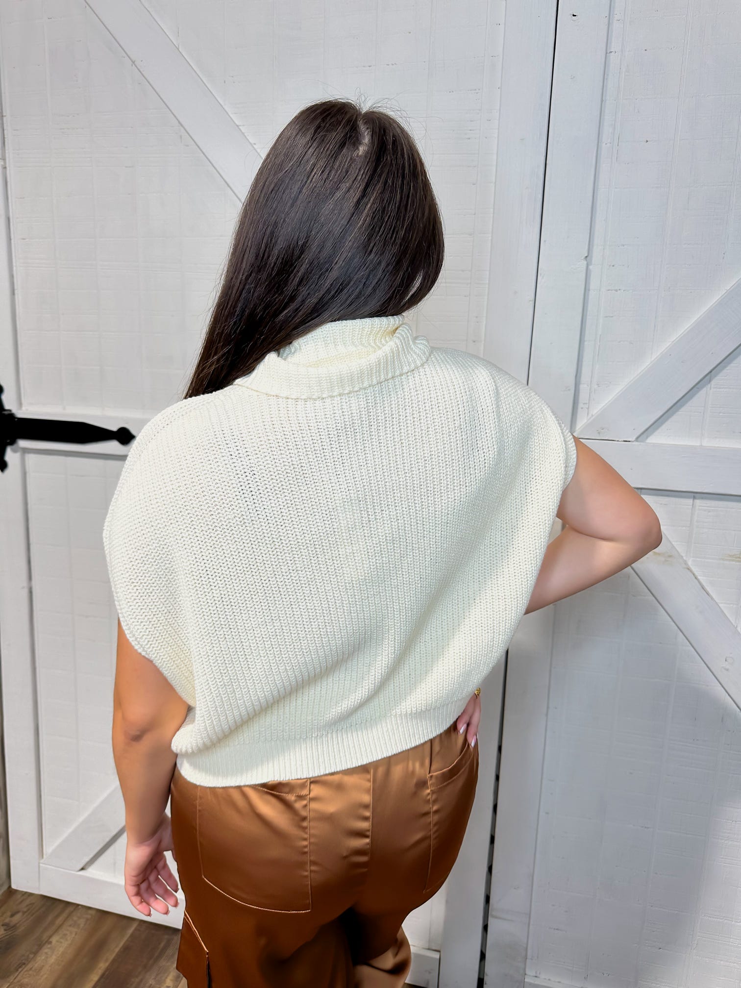 Photo of the back of our cream sweater top featuring cap sleeves and a short cowl neckline