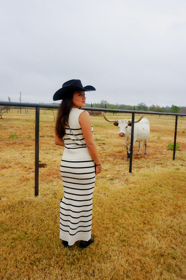 A girl modeling the back of our cream and navy stripe two piece matching sleeveless "vest-looking" sleeveless top and skirt. 