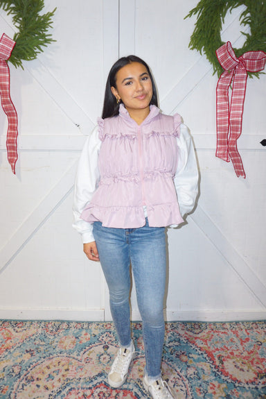 A woman modeling our lavender puffer vest with ruffles on the front and a big bow on the back