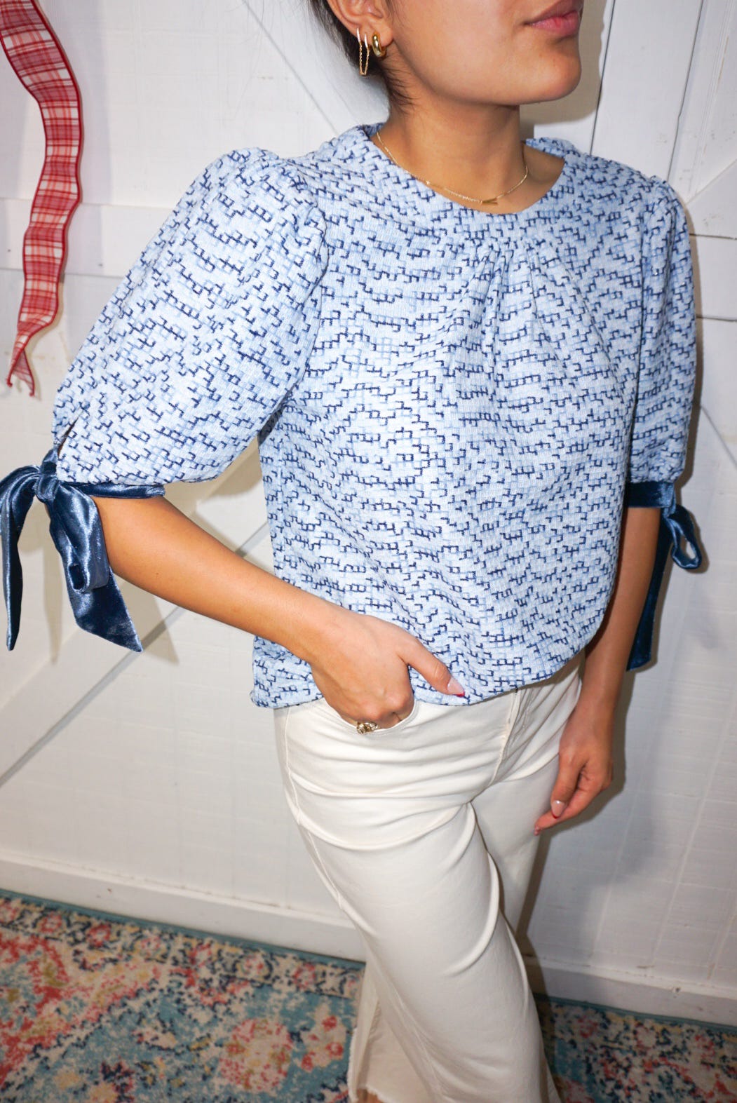 Up close photo of our blue and navy tweed blouse featuring velvet ribbon bows around the sleeves