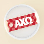 Photo showing the 40 oz tumbler lid up close. It has a red checkered background and Alpha Chi Omega written in greek letters in white on top