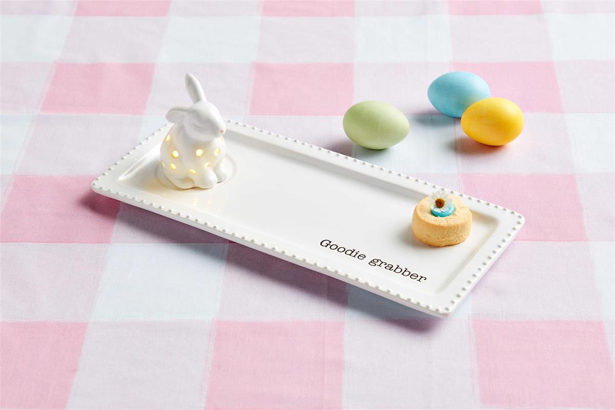 Photo showing our bunny light up ceramic sitter sitting on our goodie grabber tray. Photo shows an example of what it would look like with the sitter on the tray along with a piece of food.