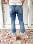 Woman modeling the back of our medium wash cropped jeans with very light distressing and a cuff at the bottom for the crop