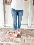 A close up photo of a woman modeling a medium wash cropped jeans with very light distressing and a cuff at the bottom for the crop