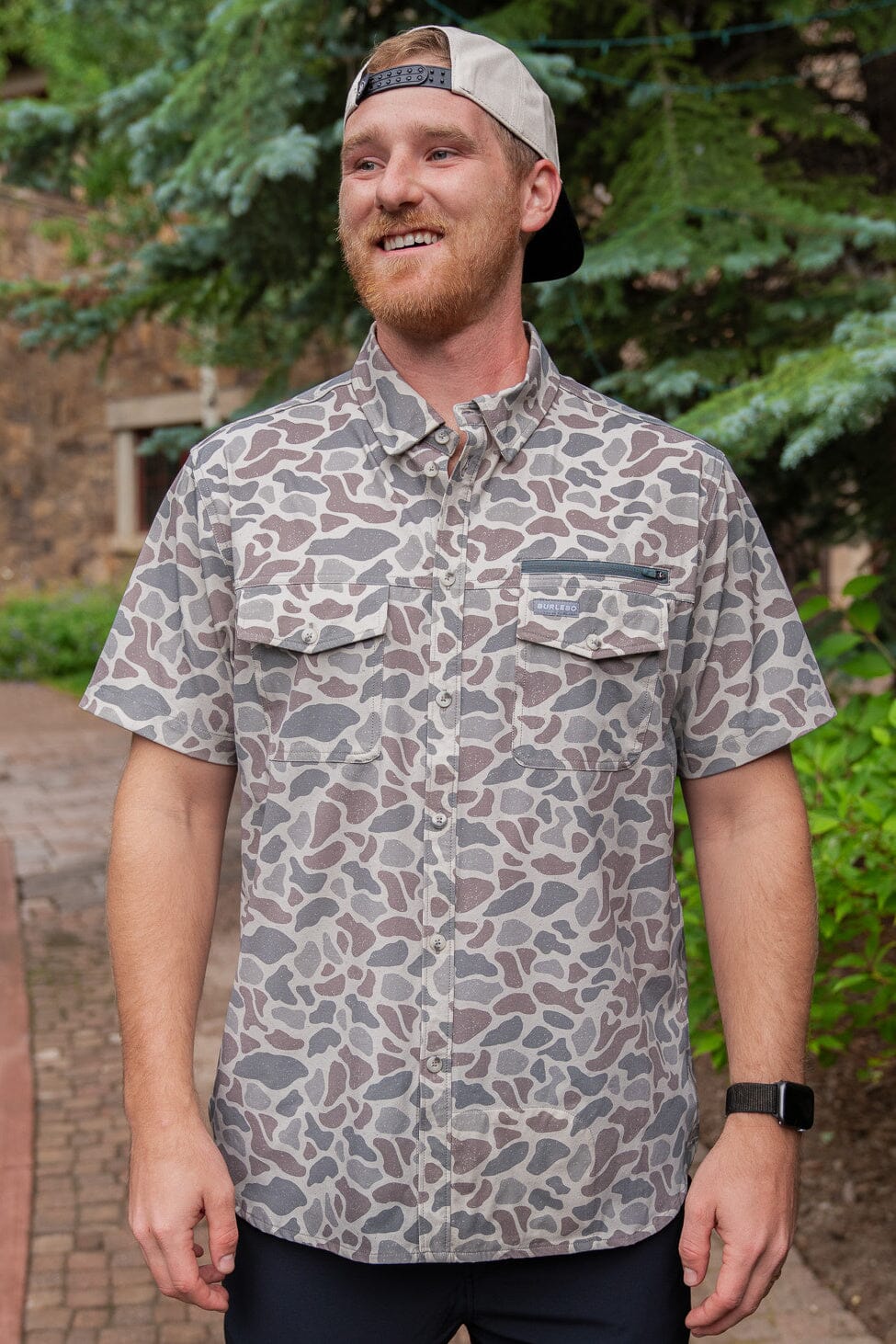 Man modeling our Performance Outdoor Deer Camo fishing shirt with UPF 50 sun protection and is made with moisture-wicking and antimicrobial material to keep you dry and fresh all day. The cape back mesh design provides comfort and breathability, perfect for long days on the water. Additionally, there is a built-in microfiber sunglasses cloth also.