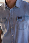 Up close photo of our light washed denim pearl snap button up short sleeve shirt